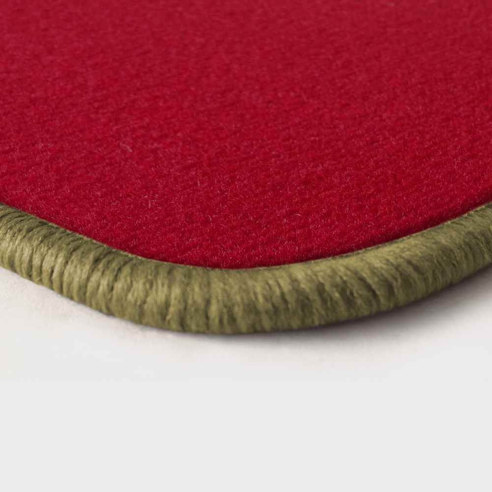 Eine Ecke als Beispiel einer Fussmatte Velours rot mit Rand in beige.