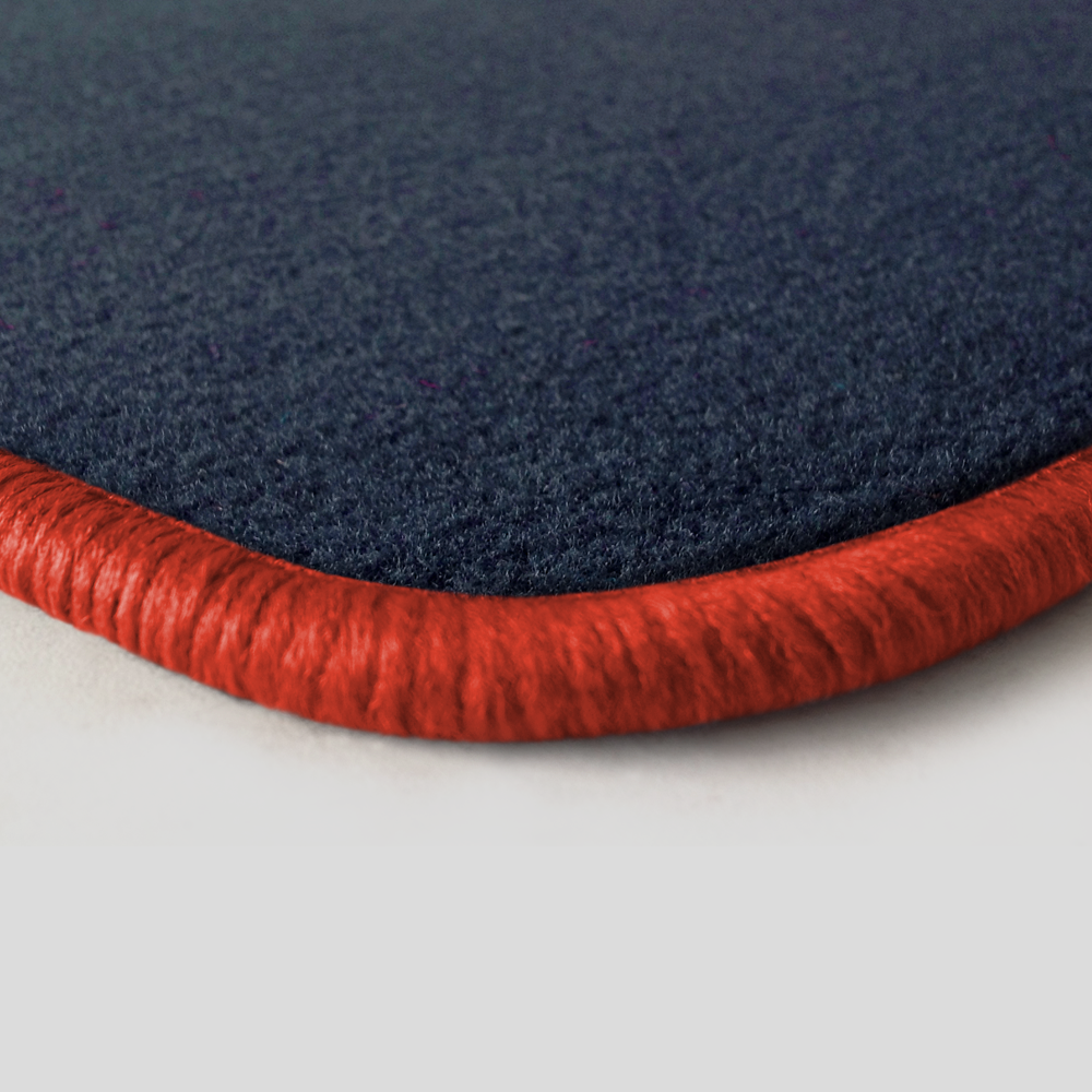 Eine Ecke als Beispiel einer Fussmatte Velours dunkelblau mit Rand in orange.