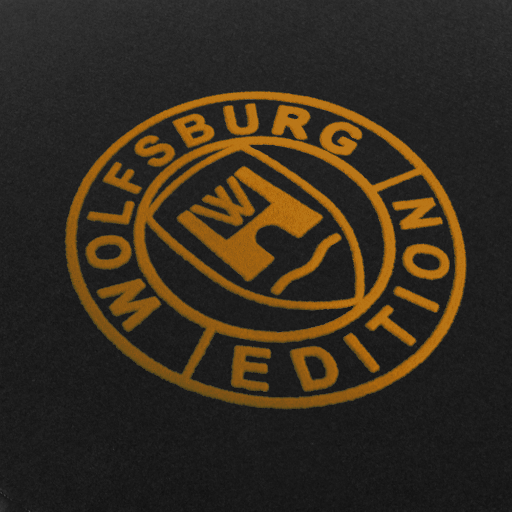 Das Wolfsburg Editions Logo auf einem schwarzen Teppich und das Logo ist in gold.