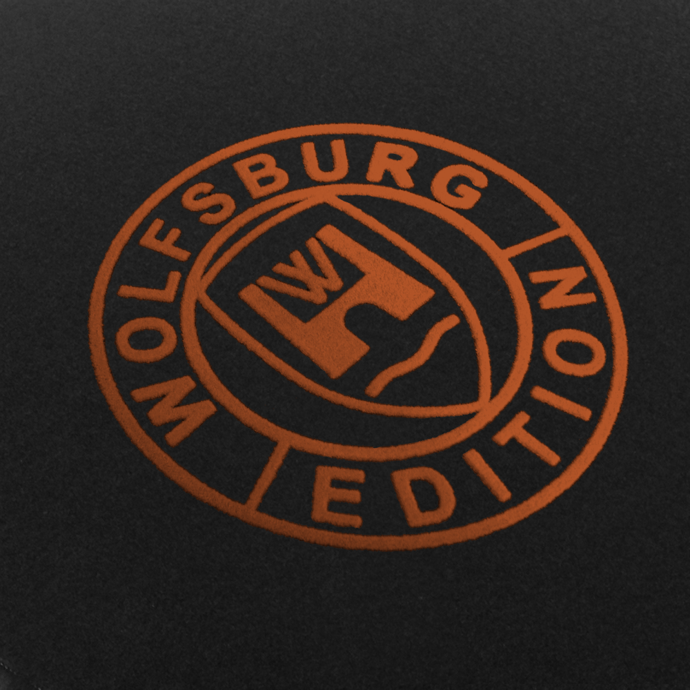 Das Wolfsburg Editions Logo auf einem schwarzen Teppich und das Logo ist in kupfer.